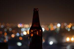 Bottle of home brewed beer city lights behind