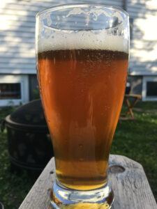 Craft beer in beer glass outside with fire pit in back ground