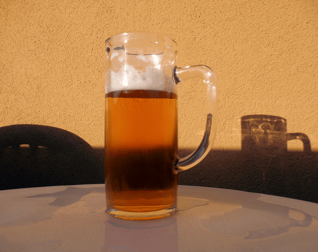 Homebrew beer sitting on a table with shadow behind it