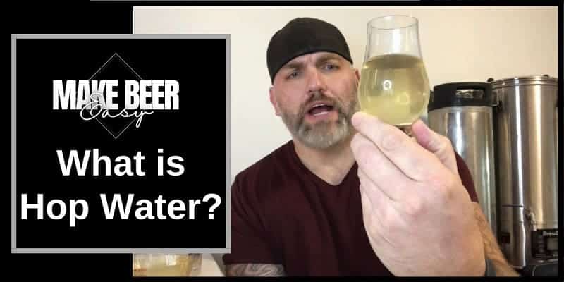 A man explaining what is hop water as he holds up a small glass of hop water.